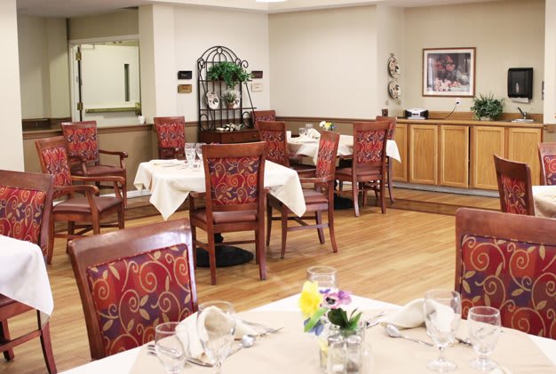 An elegantly set dining area with tables and chairs, featuring decorative elements and floral centerpieces.
