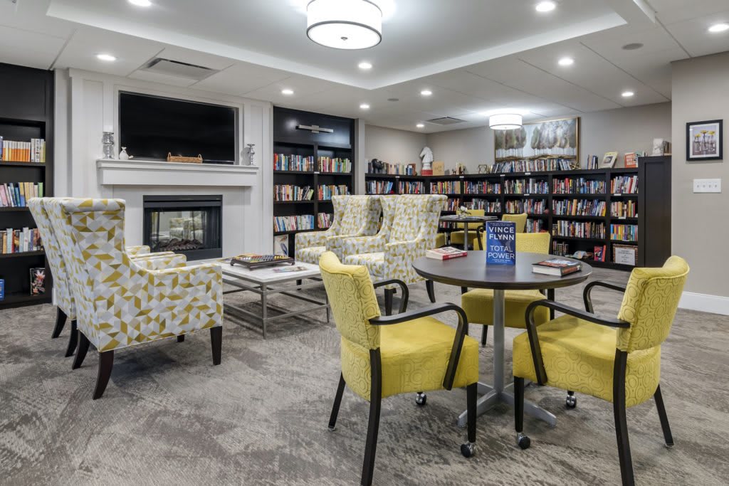 A cozy library with comfortable seating and a fireplace.