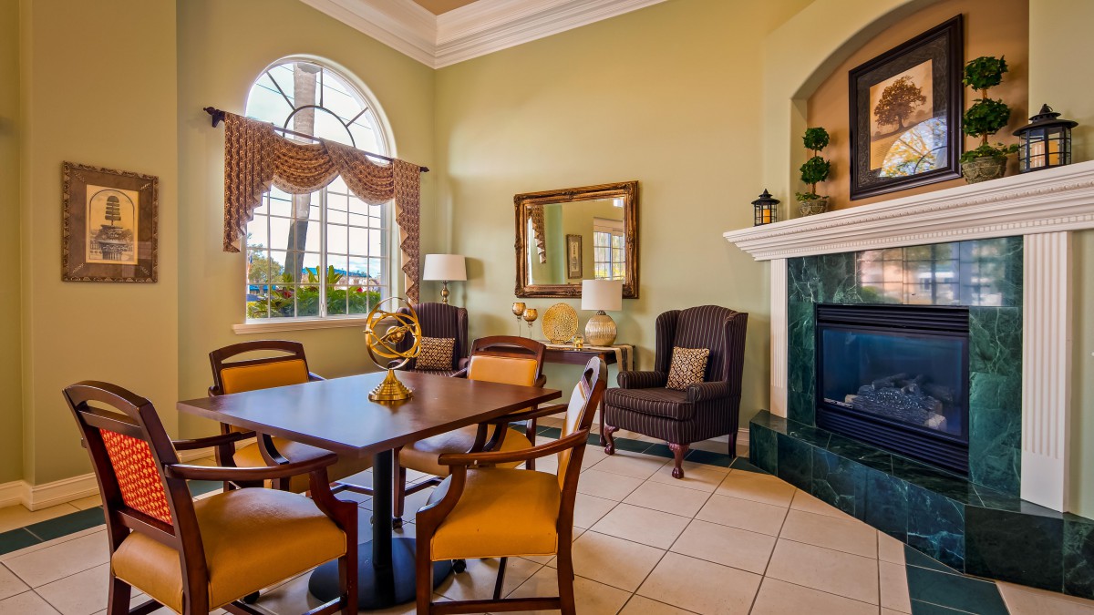 A cozy living room with a dining area and fireplace, featuring elegant furniture and large windows.