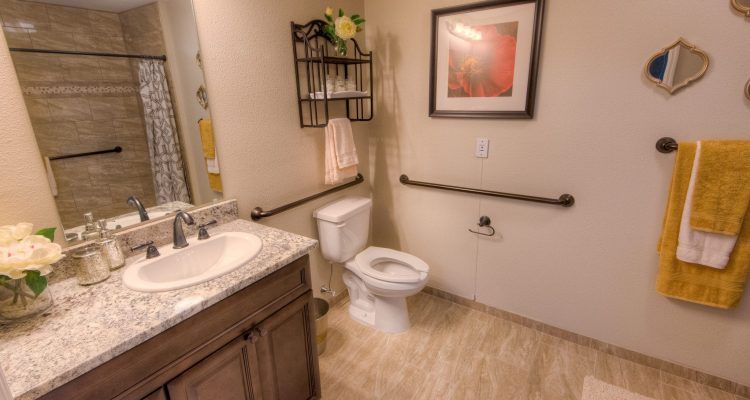A well-organized bathroom with a sink, toilet, towel rack, and wall decor.