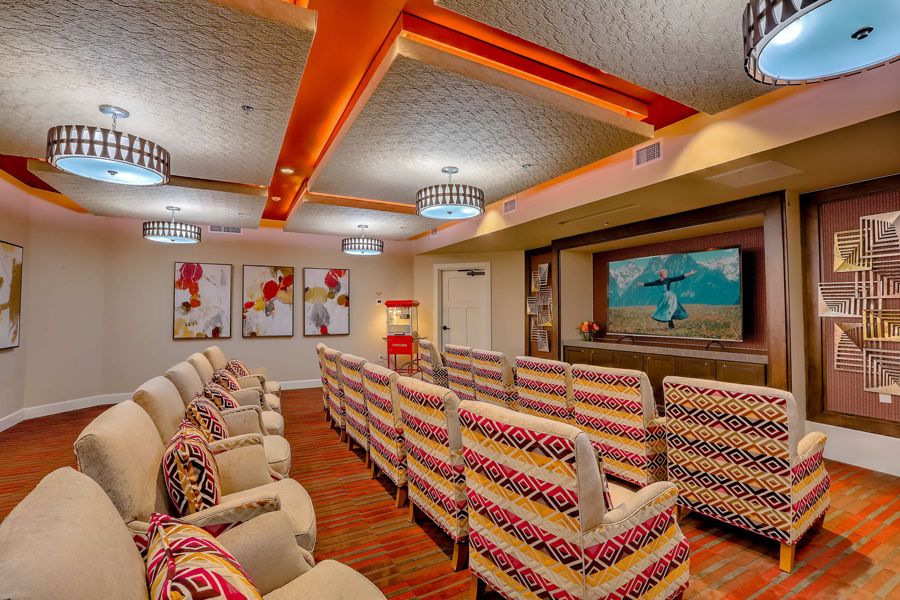 A cozy theater room with patterned seating and vibrant artwork on the walls.