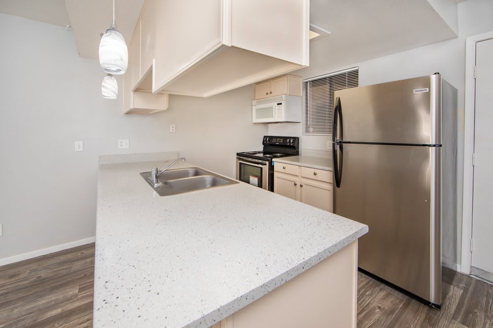 A modern kitchen with a sleek countertop, stainless steel appliances, and pendant lighting.
