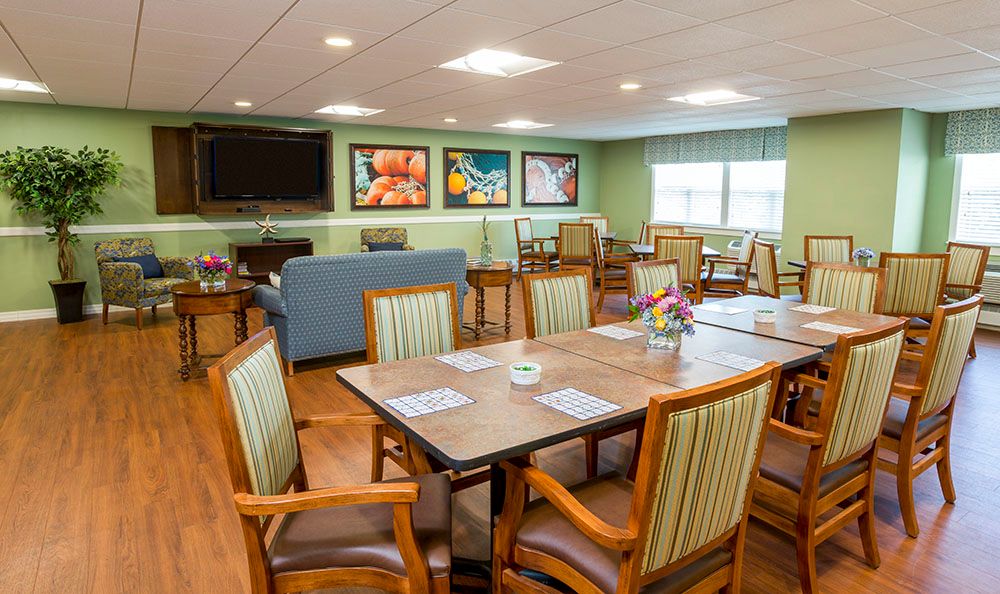 A cozy dining area with tables, chairs, wall art, and a television.