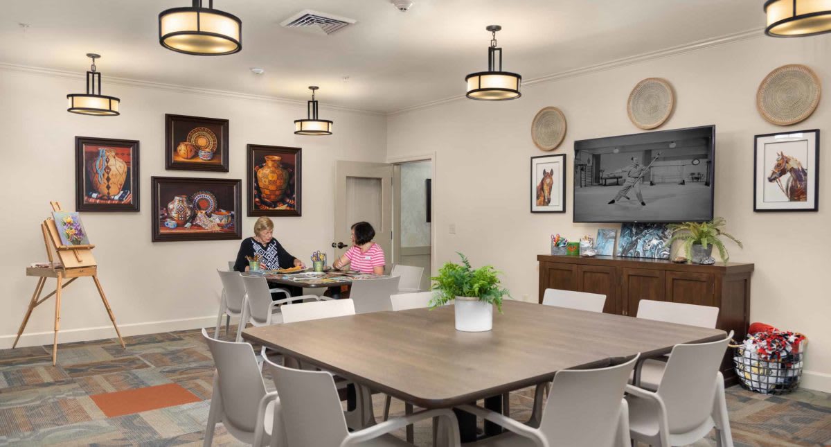 A cozy dining area with people engaged in conversation, surrounded by artwork and modern decor.
