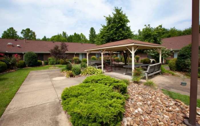 A charming garden area featuring a gazebo, surrounded by lush greenery and a pathway.