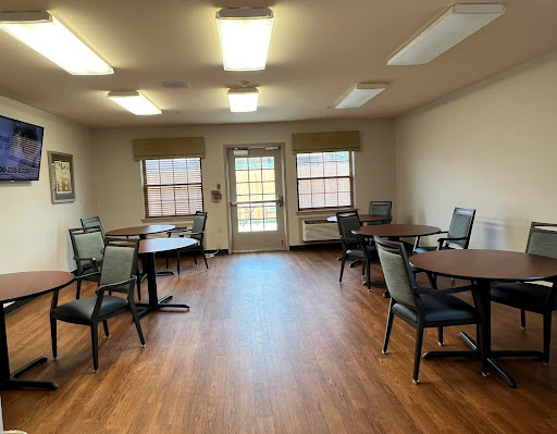 A spacious and well-lit room featuring tables and chairs, ideal for gatherings or activities.