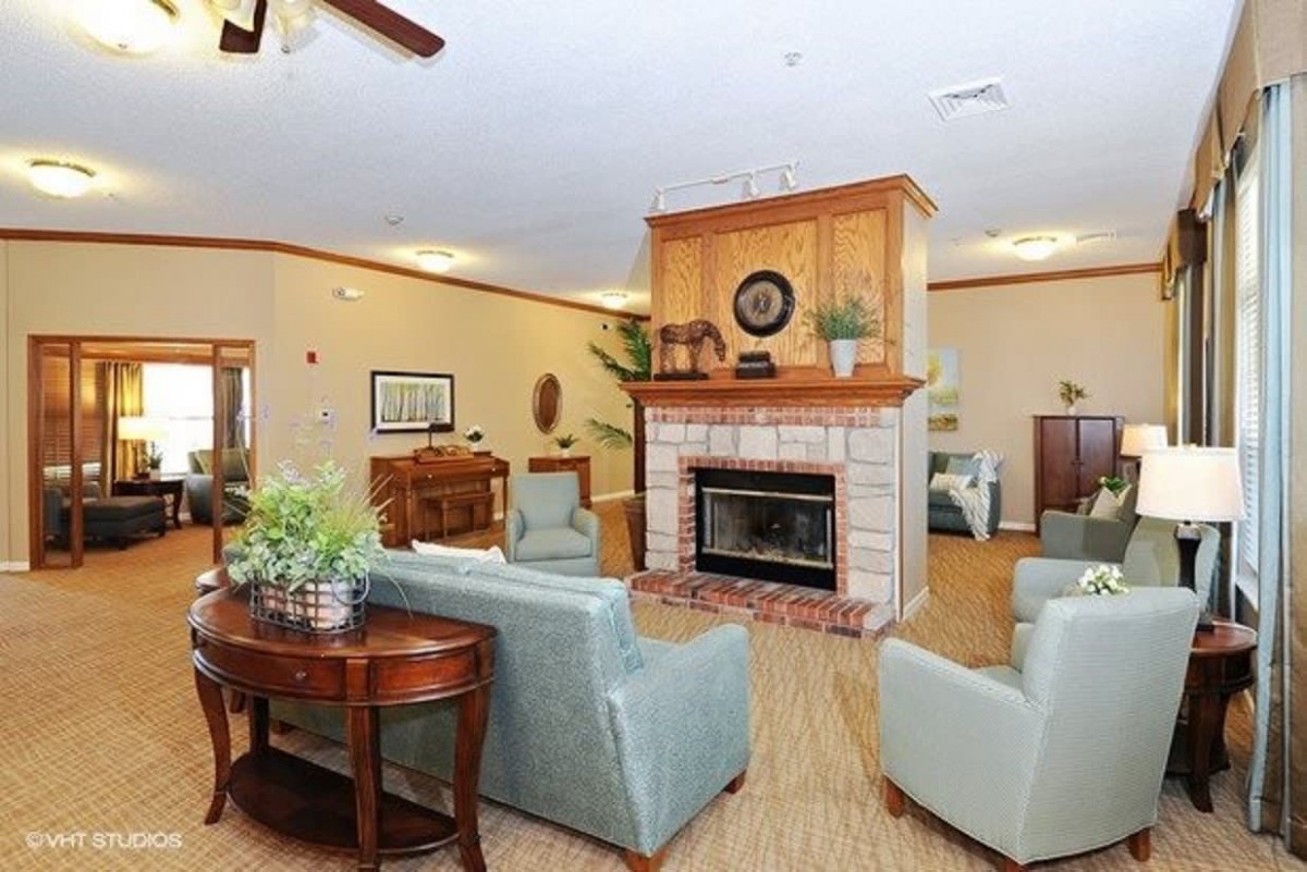 A cozy living room with a fireplace, comfortable seating, and decorative plants.
