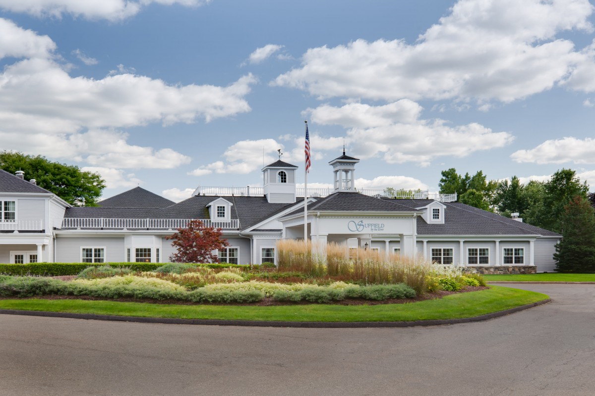 A well-landscaped building with a flagpole and a cloudy sky backdrop.