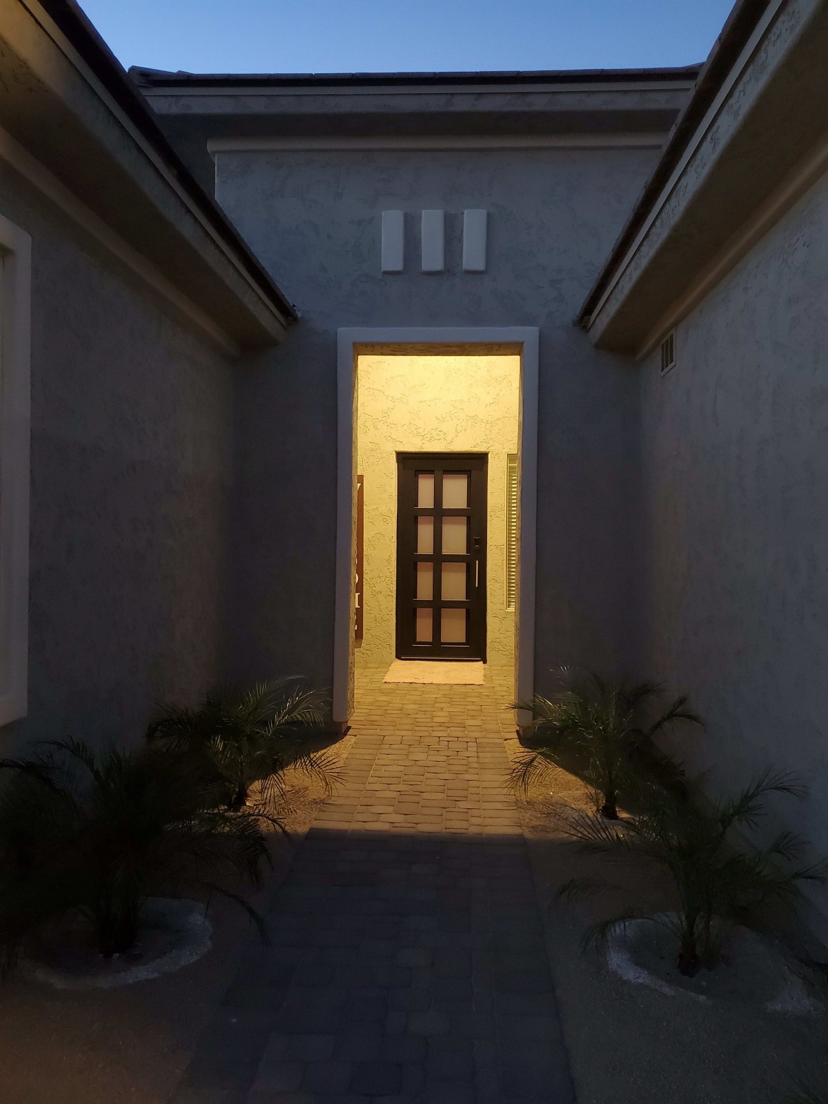 A well-lit entrance pathway leading to a front door at night.