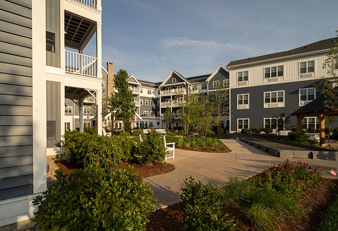 A modern apartment complex with well-maintained landscaping and outdoor seating.