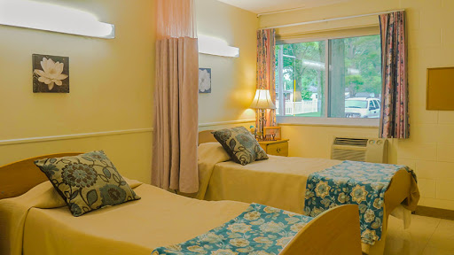 A cozy hotel room featuring two twin beds, soft yellow walls, and plenty of natural light.
