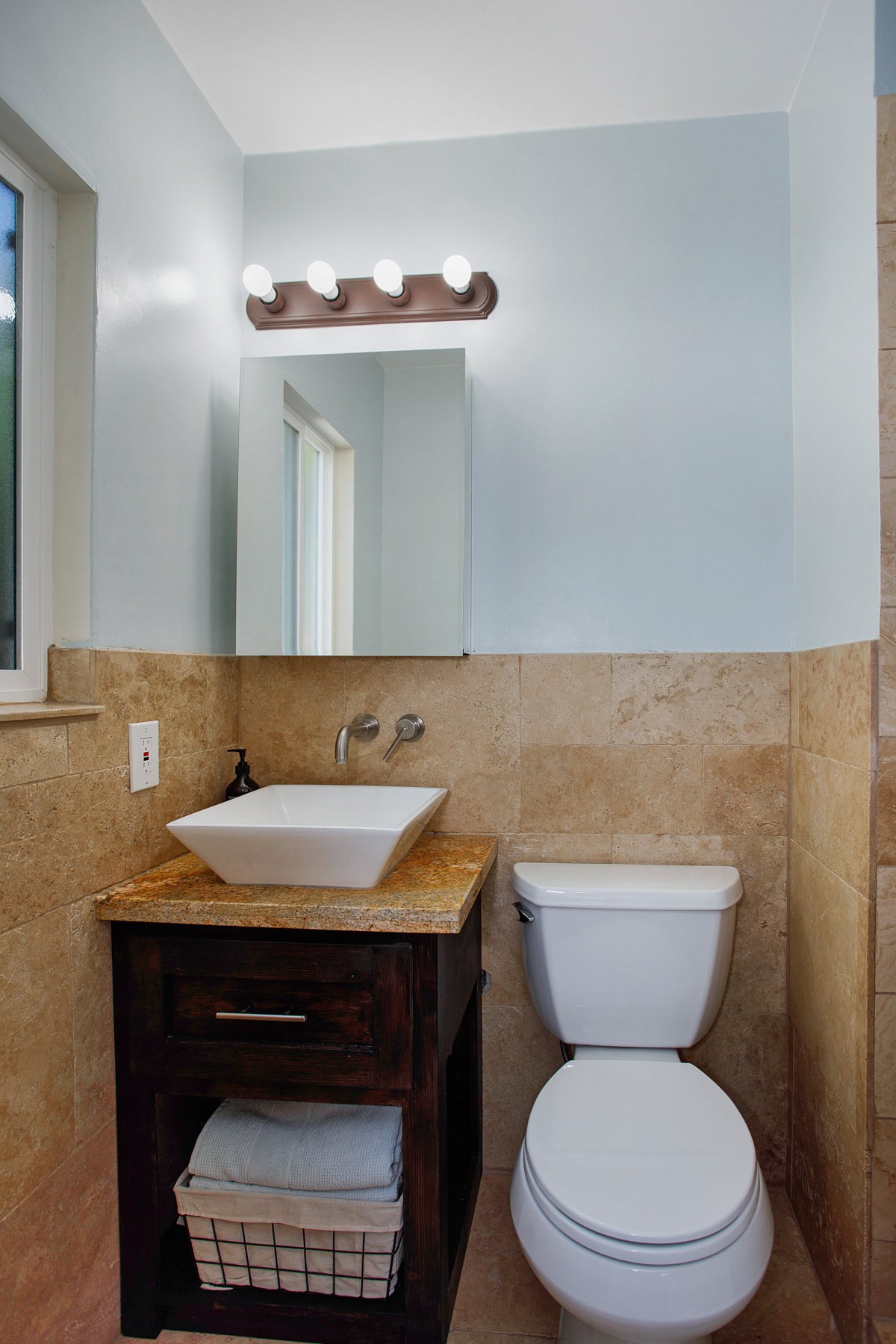 A modern bathroom featuring a square sink, wooden vanity, and tiled walls.