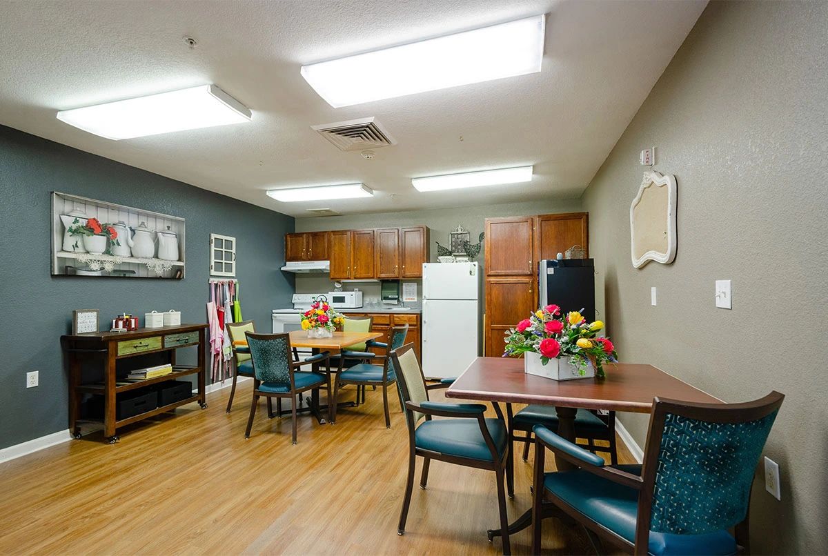 A communal kitchen and dining area with tables, chairs, and appliances.