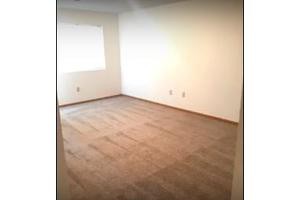 An empty room with carpeted flooring and a window, ready for decoration.