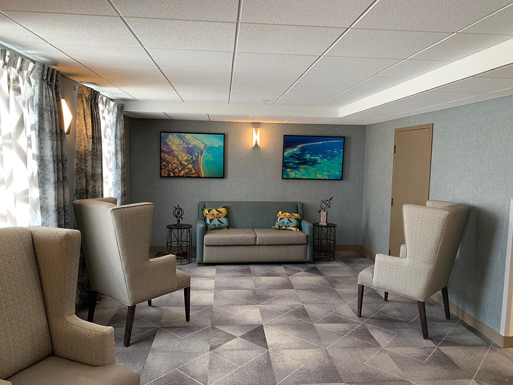 A modern living room with a sofa, chairs, and wall artwork.