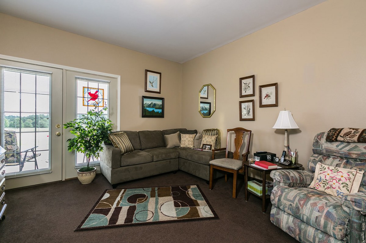 A cozy living room with a sectional sofa, armchair, and decorative elements including a rug, wall art, and a potted plant.