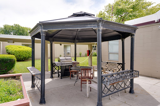 A stylish gazebo in a landscaped outdoor area, featuring seating and a grill.