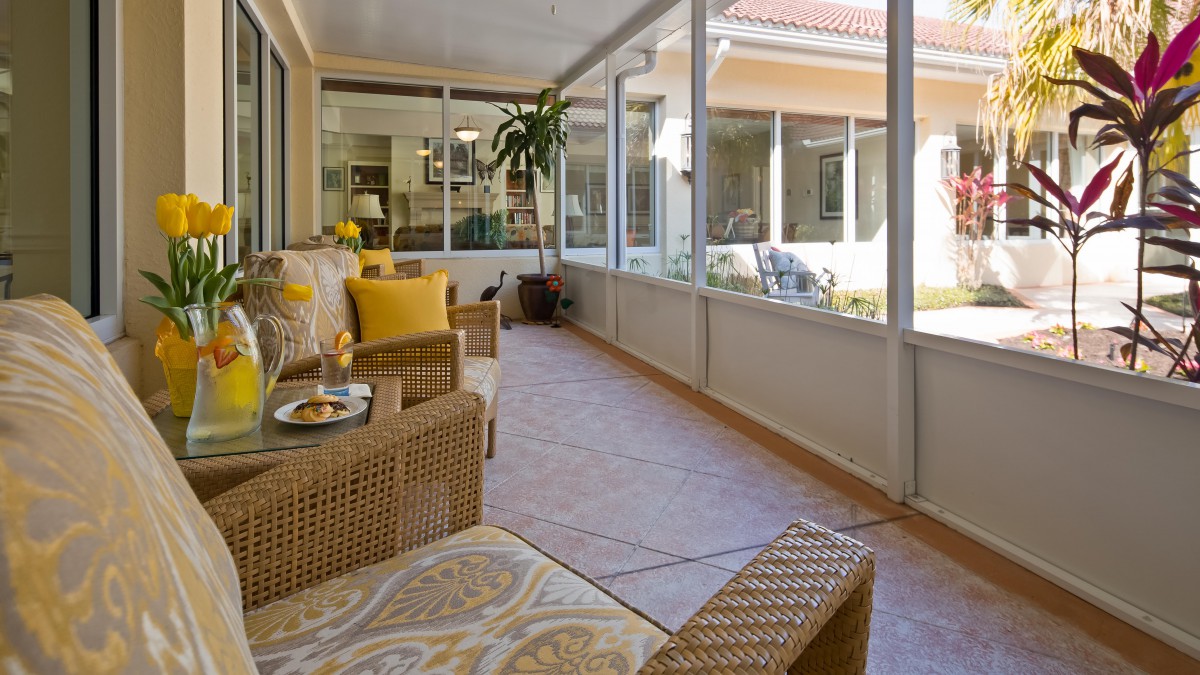 A cozy sunroom with wicker furniture and large windows.
