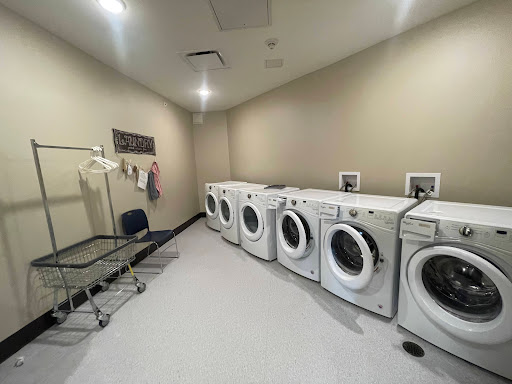 A spacious laundry room equipped with multiple washing machines and a drying rack.