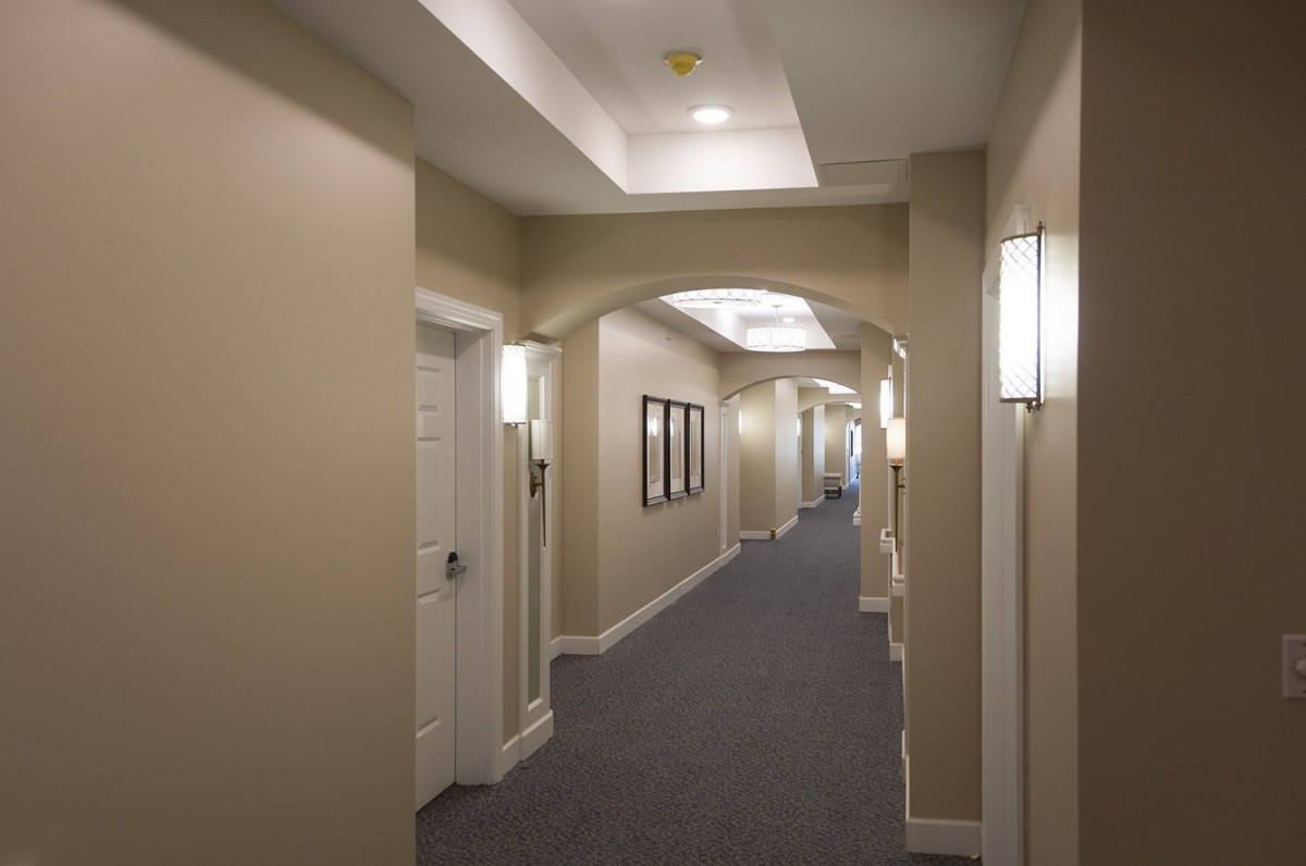 A well-lit hallway with multiple doors and carpeted flooring.
