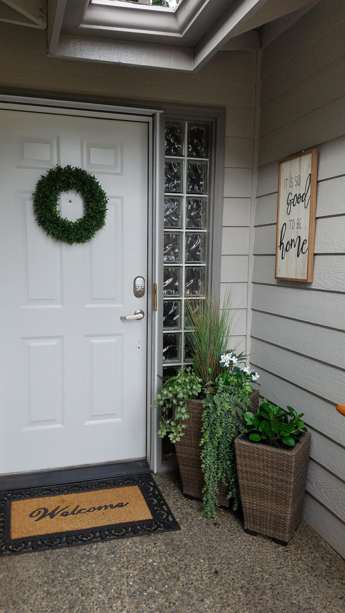 A welcoming front porch with a wreath on the door and potted plants.
