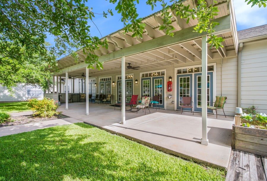 A spacious covered patio with outdoor seating overlooking a lush green lawn.