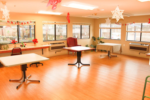 A spacious and well-lit indoor room featuring multiple tables and a cozy chair, decorated for a special occasion.