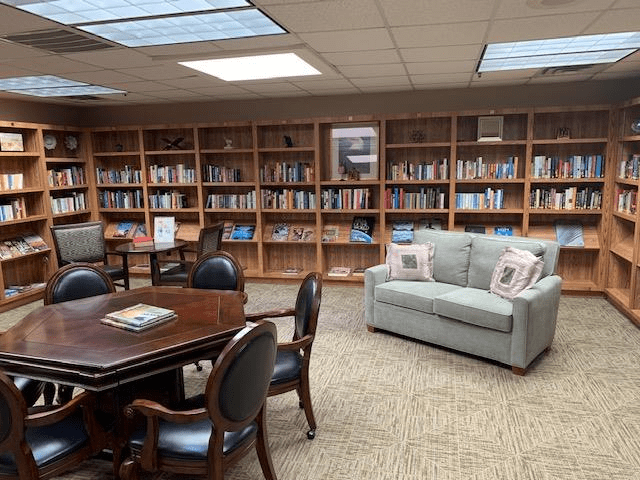 A cozy library space with bookshelves, a sofa, and seating area for reading.