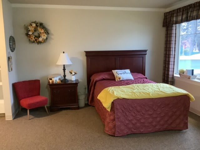 A cozy bedroom with a neatly made bed, nightstand, and decorative items.