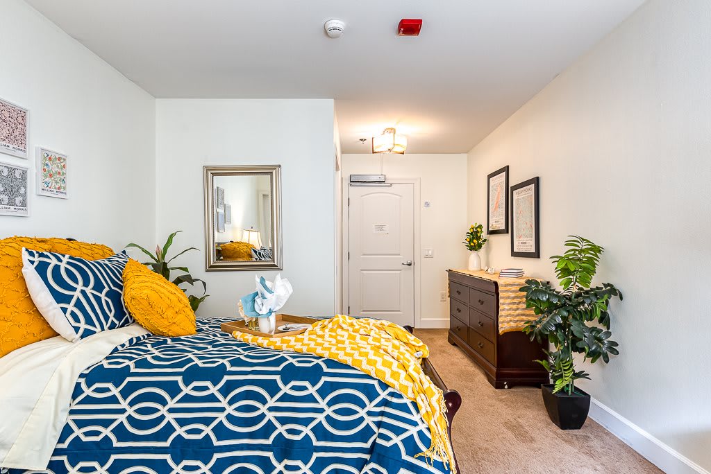 A modern bedroom with colorful bedding, decorative plants, and stylish furnishings.