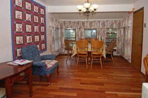 A cozy dining area featuring a wooden table surrounded by chairs and large windows with patterned curtains.