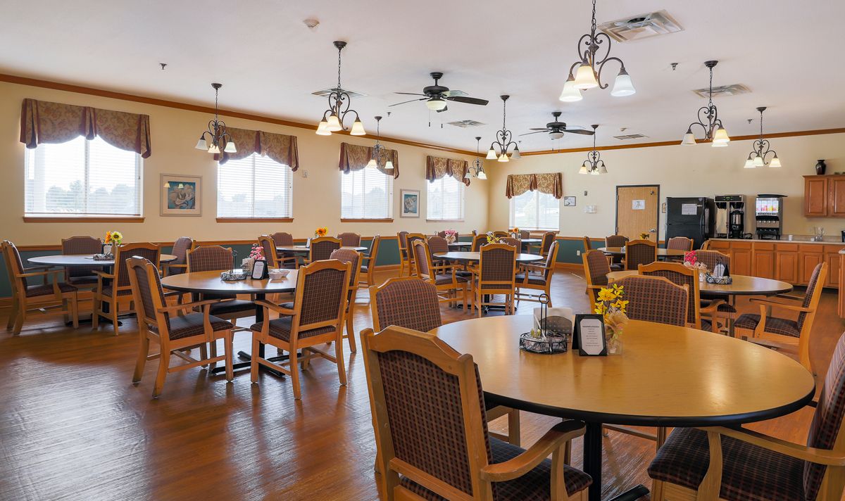A spacious dining area with wooden chairs and tables, decorated with ceiling fans and elegant lighting.