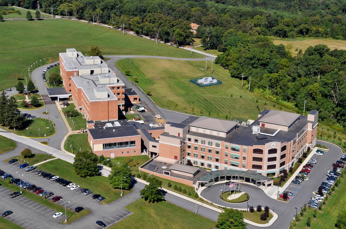 Aerial view of a large hospital complex surrounded by greenery and parking lots.
