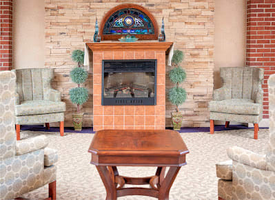 A cozy living room setup with a central fireplace, surrounded by elegant chairs and a wooden table.