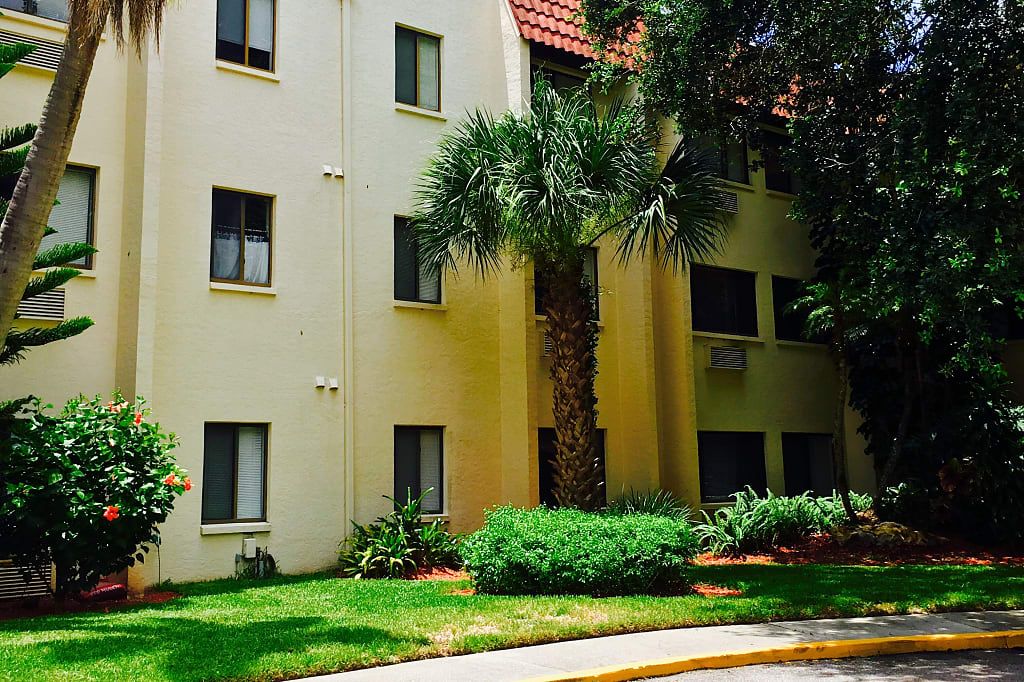 A residential apartment building with palm trees and well-maintained landscaping.