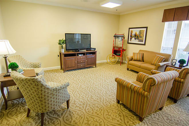 A cozy living room with a TV, sofas, chairs, and a popcorn machine.