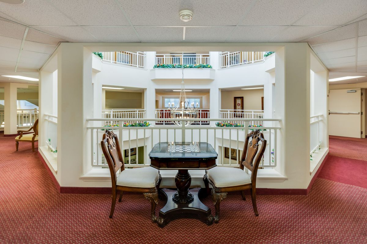 A classic interior view featuring a small table and chairs set against an open atrium backdrop.