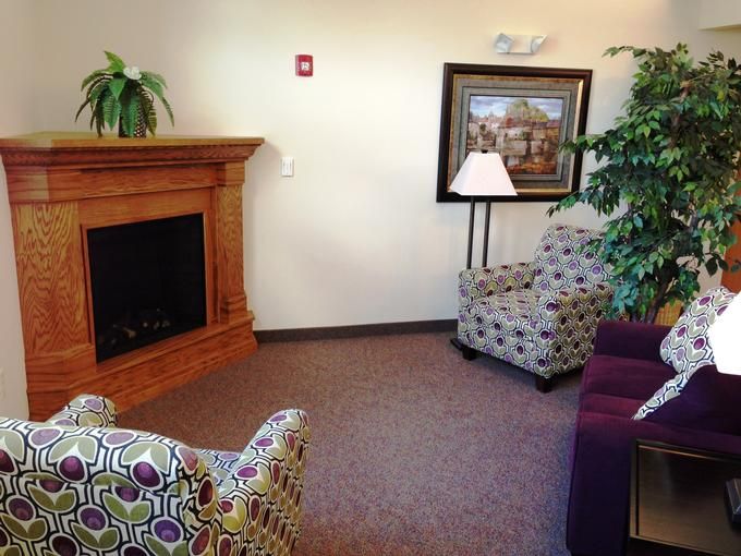 A cozy living room corner featuring a fireplace, patterned chairs, and tasteful decor.