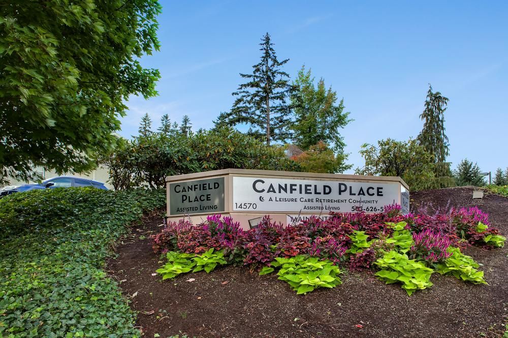 A well-maintained entrance sign surrounded by colorful plants and shrubs.