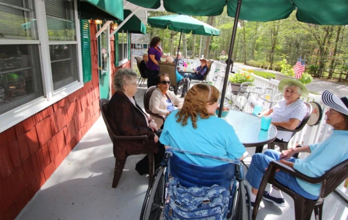 A group of people socializing on an outdoor patio with umbrellas.