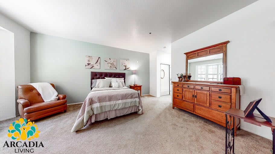 A cozy bedroom with a neatly made bed, wooden dresser, and soft carpet.