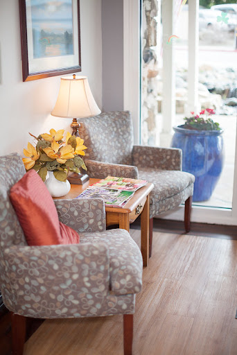 A cozy corner of a living room featuring comfortable chairs, a lamp, and decorative elements.
