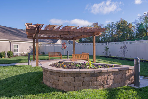A serene garden space featuring a wooden pergola, well-maintained flowerbeds, and inviting seating areas.