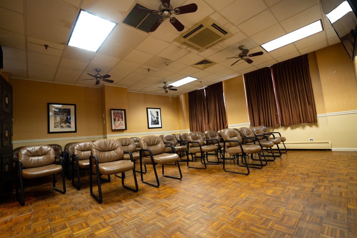 An empty conference room with rows of chairs and ceiling fans.