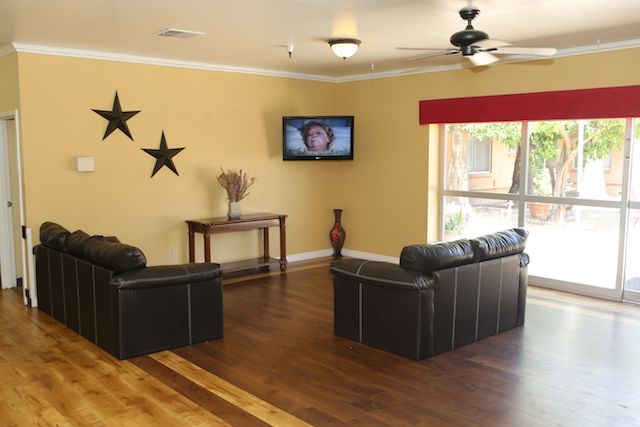 A cozy living room with a sofa set, TV mounted on the wall, and decorative elements such as wall stars and a vase.