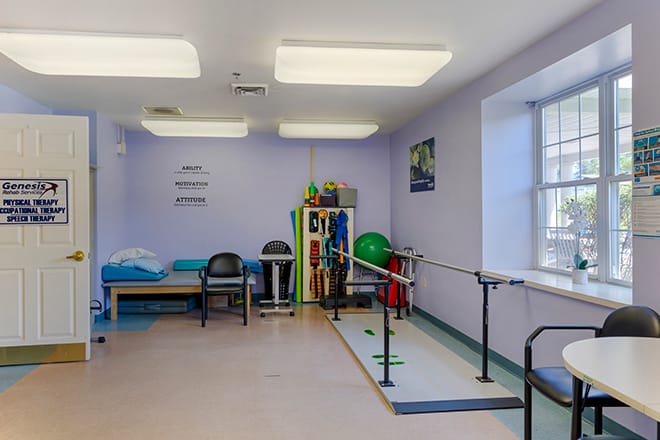 A physical therapy room equipped with parallel bars, exercise balls, and a treatment table.