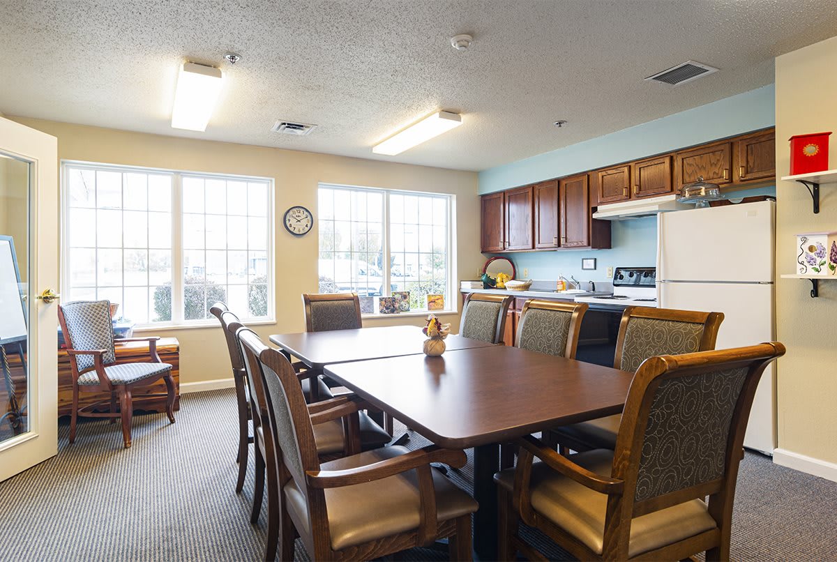 A spacious dining area with a large table and chairs, connected to a kitchen with ample natural light streaming through the windows.