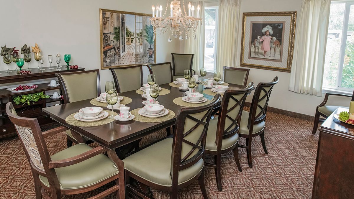 A well-decorated dining room with a set table and elegant chandelier.