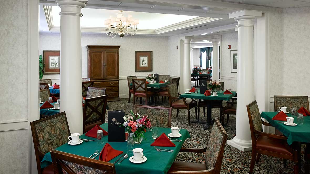 A neatly arranged dining room with tables set for a meal, featuring a chandelier and elegant decor.