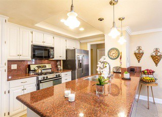 A modern kitchen with white cabinets, stainless steel appliances, and a large granite countertop.